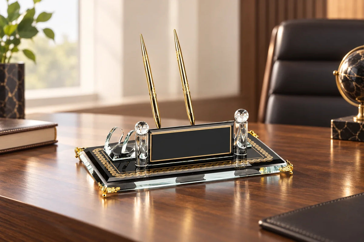 Plaque nominative en verre noir et transparent avec stylos dorés sur un bureau en bois