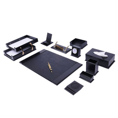 Black desk accessory arrangement with a writing pad, two-tier document tray, clock, tissue box and gold-colored pens.