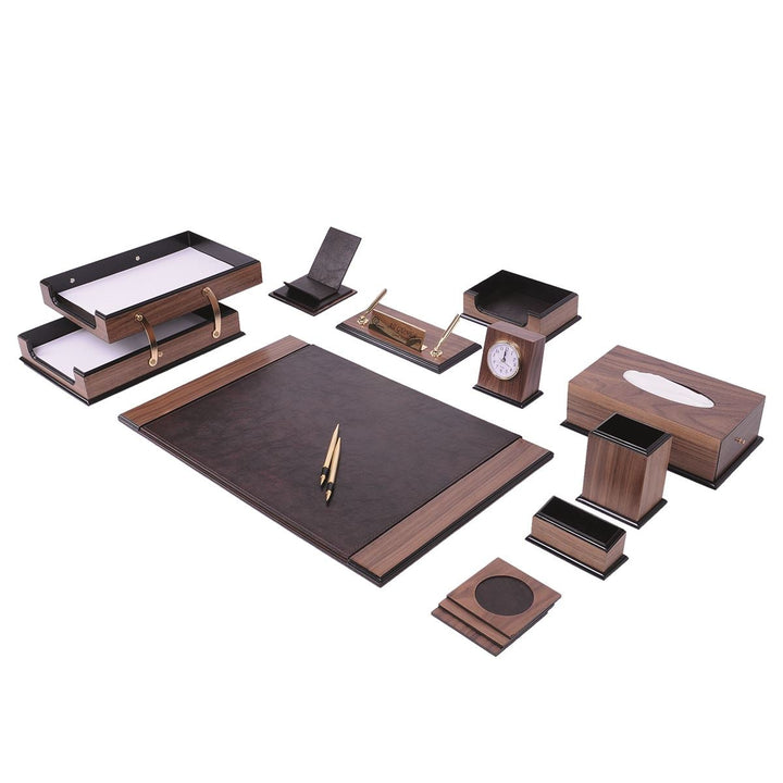 Brown desk accessory arrangement with a dark writing pad, two-tier document tray, clock, tissue box and gold-colored pens.