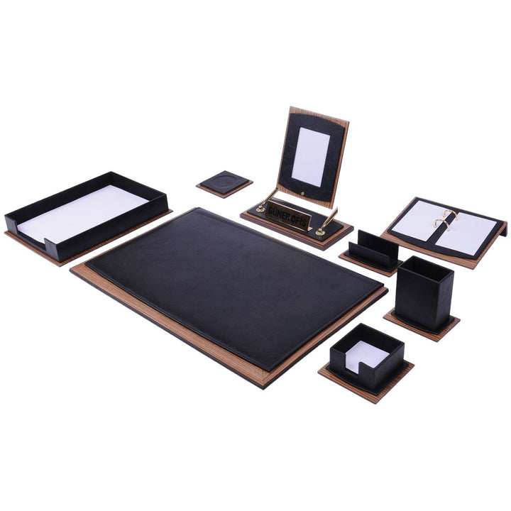 A matching desk organizer set featuring a large black desk mat with a brown leather-look border, a black tray, a black stand with a white insert, a black notebook, a black folder, and small black boxes, all arranged on a plain white background.