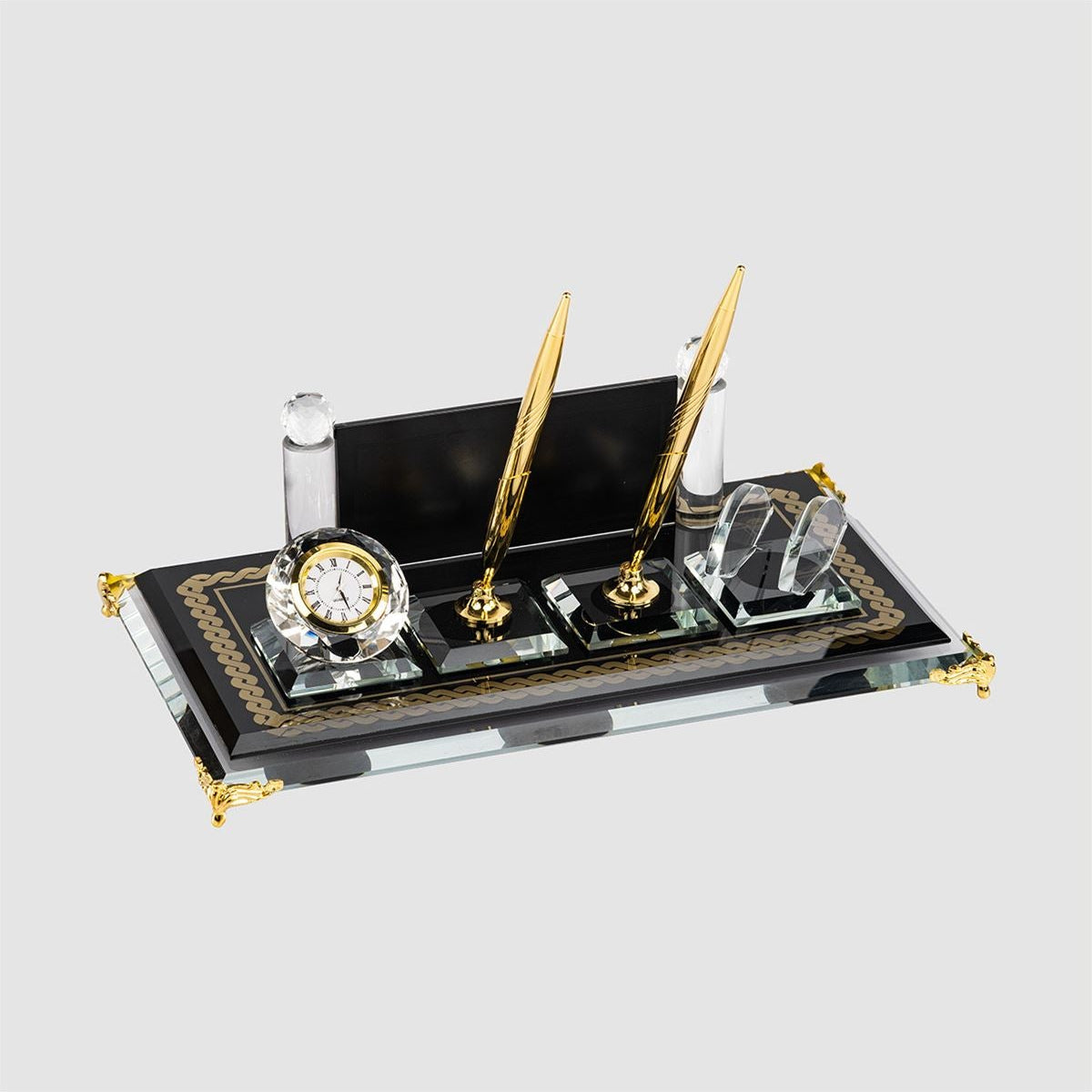 Black glass desk nameplate set with two gold-tone pens, a clock and a clear card holder, viewed at an angle