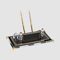 Dark glass desk nameplate with gold-colored edging, two gold-colored pens, a curved card holder and decorative upright posts.