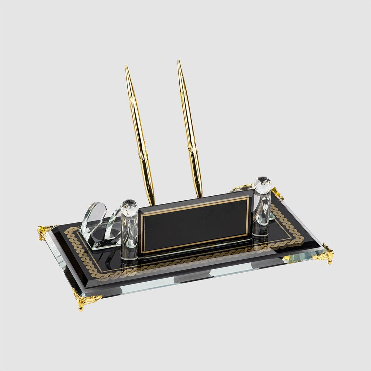 Dark glass desk nameplate with gold-colored edging, two gold-colored pens, a curved card holder and decorative upright posts.