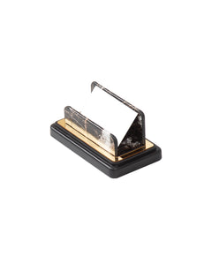 Dark marble-pattern business card holder with an angled back, gold-colored trim and a black base.